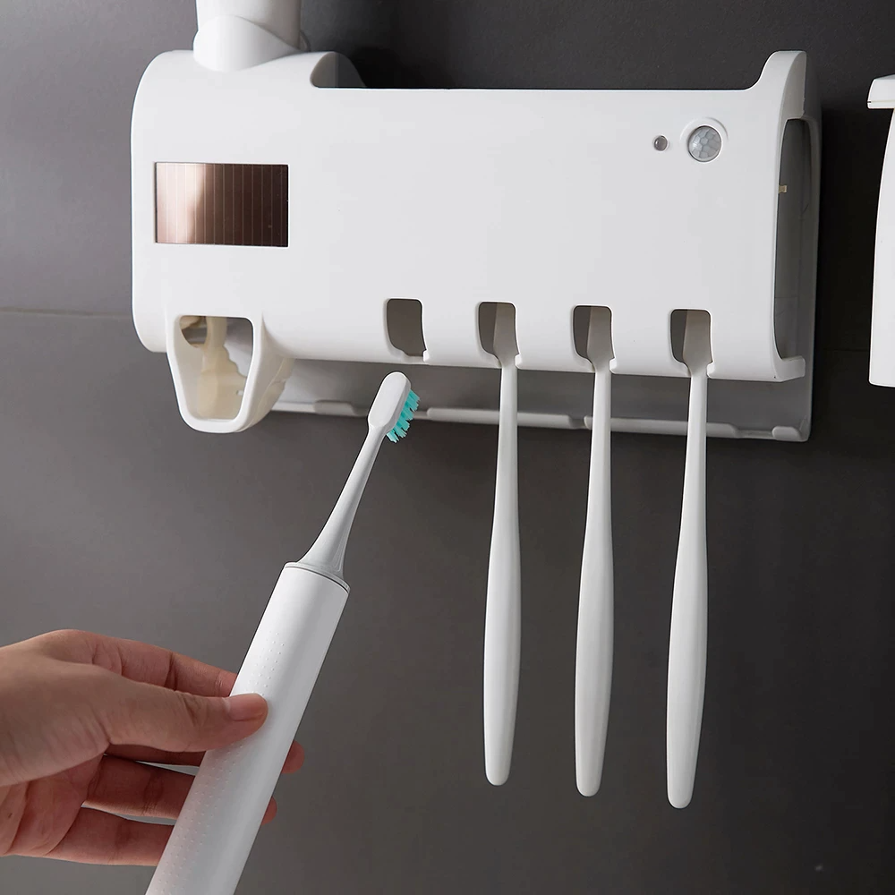 UV toothbrush sanitizer station mounted on the wall holding four brushes